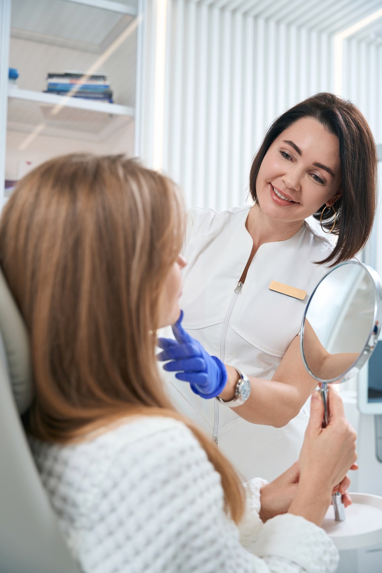 woman sits in chair and holdsa mirror in her hands